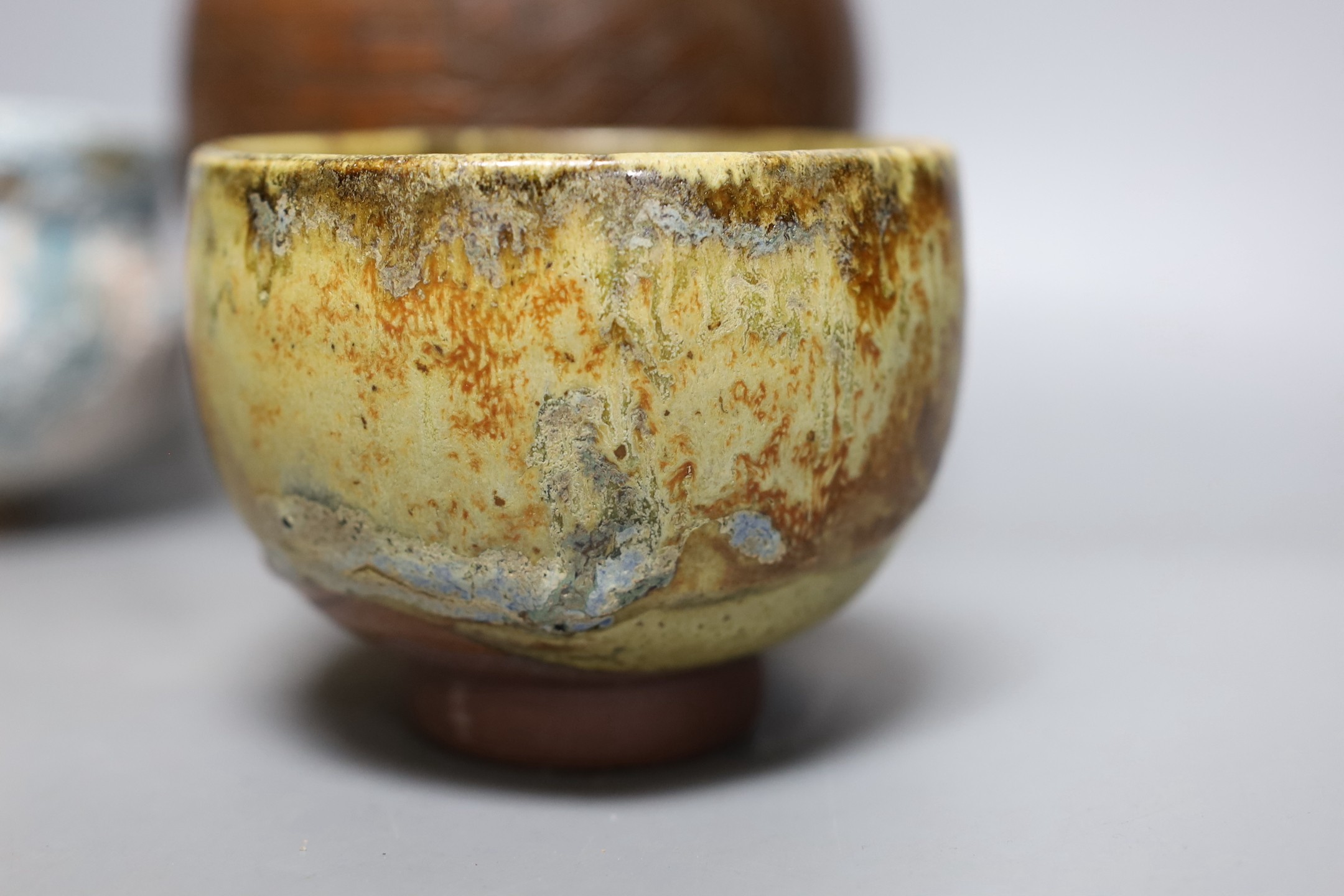 Two Japanese stoneware tea bowls (chawan), a Japanese raku bowl and a Japanese carved wood tea caddy, 19cm